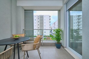 A balcony with a table, chairs, a bowl of fruit, and a potted plant. - Splitful Apartment (Split)