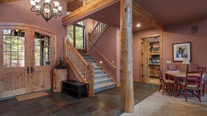 A spacious interior with a wooden staircase, a dining area, and a kitchen visible through an open door. - GH261 | Amazing Luxury home sure to be your new favorite! (Black Butte Ranch)