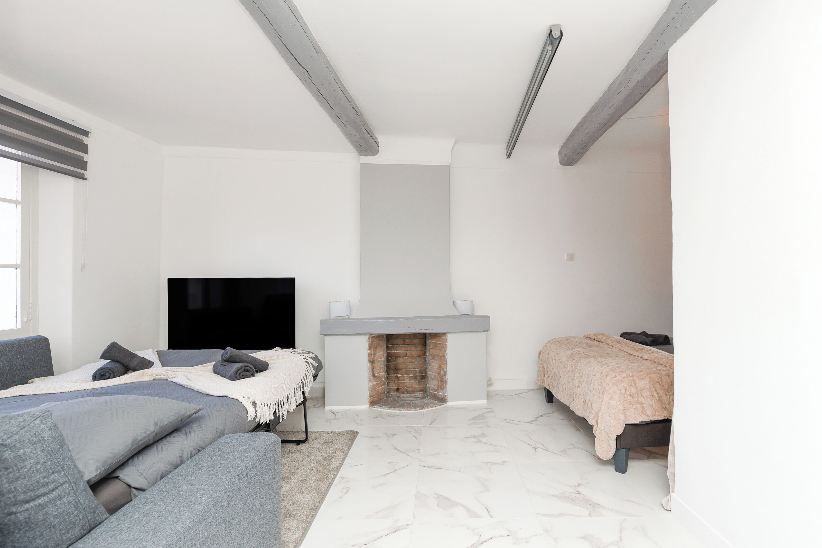 Une chambre à coucher moderne avec une cheminée, un lit, un canapé et un téléviseur.