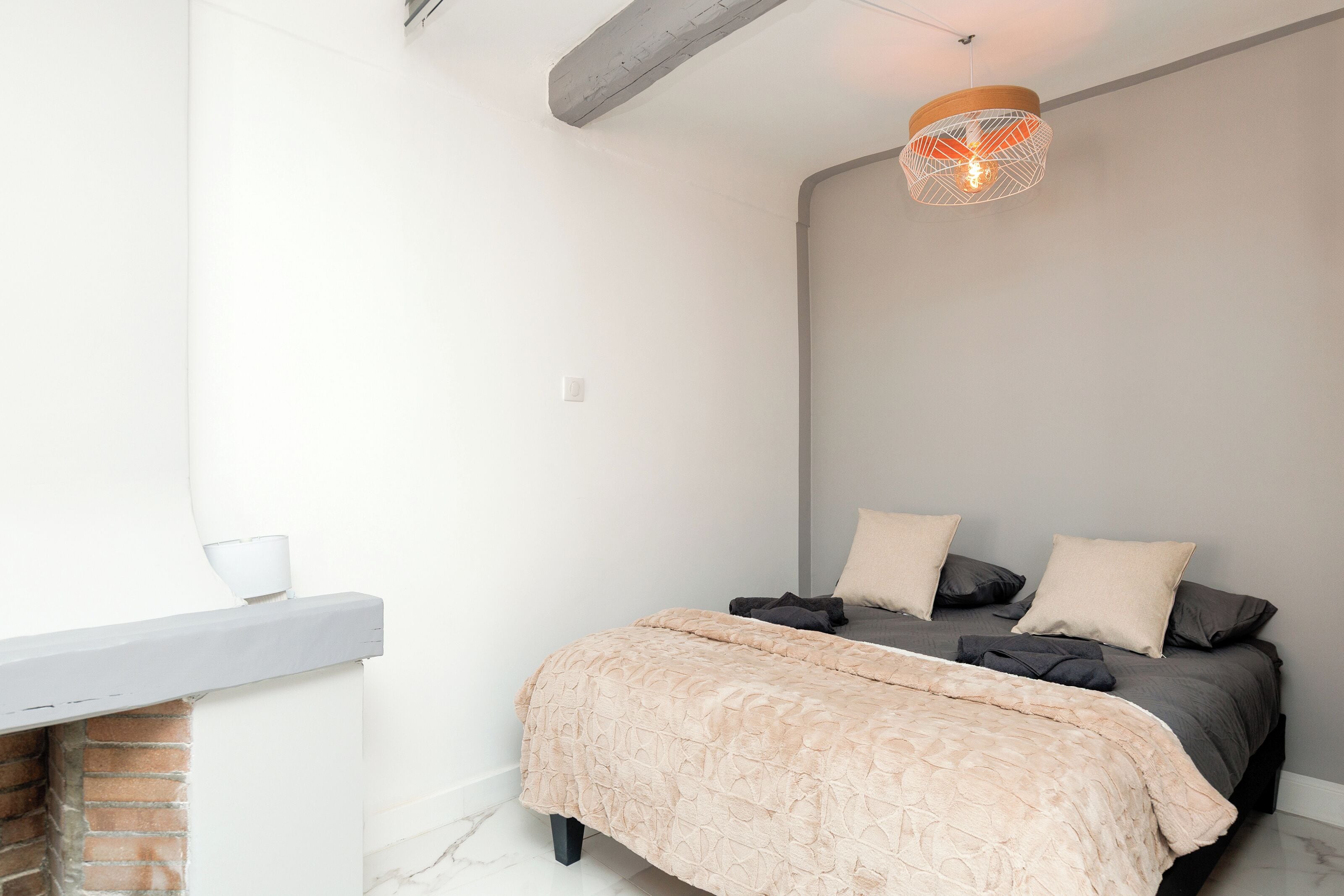 Une chambre à coucher avec un lit, un luminaire suspendu et une cheminée.