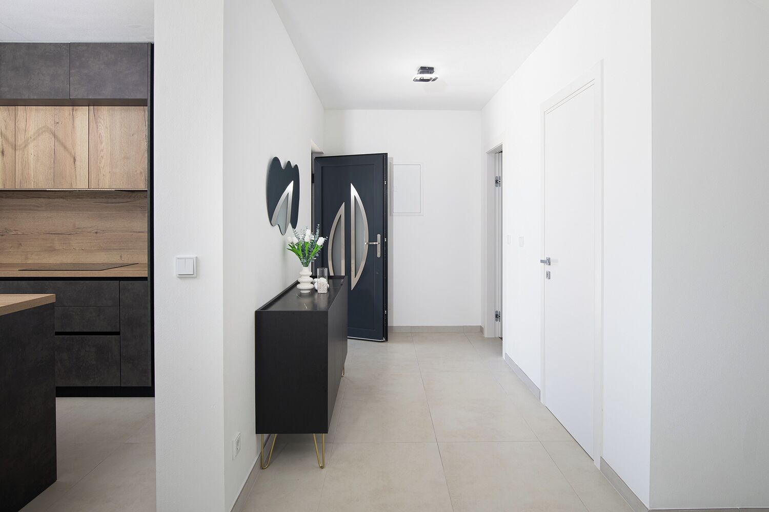 A modern hallway with a black console table, a wooden shelf, and a black door with a unique design.