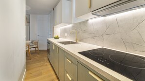 Une cuisine moderne dotée d’un dosseret en marbre, d’un évier en acier inoxydable et d’une plaque de cuisson à induction noire.