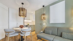 Un salon moderne avec un canapé gris, une table basse en bois et un coin repas comprenant une table ronde et quatre chaises.