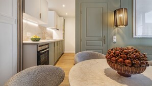 Une cuisine moderne dotée d’un plan de travail en marbre, d’un four encastré et d’un coin repas avec une table ronde et deux chaises.