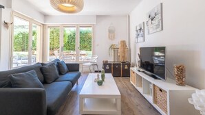 Een moderne woonkamer met een bank, salontafel, televisie en kunstwerk.