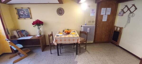 Un petit coin repas avec une table dressée pour deux personnes, un vase rempli de fleurs et un radiateur fixé au mur.