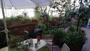 Ein möblierter Außenbereich mit Terrassentisch für zwei Personen, umgeben von Topfpflanzen und einem Stuhl.