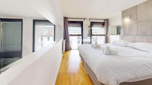Une chambre d’hôtel moderne avec un grand lit, une vue par la fenêtre et un plancher en bois.