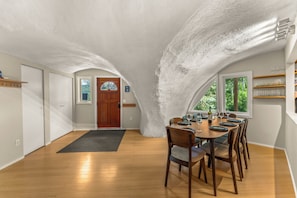 Enjoy dining and socializing in this spacious room with a vaulted ceiling, dining table, and window offering a view of the outdoors.