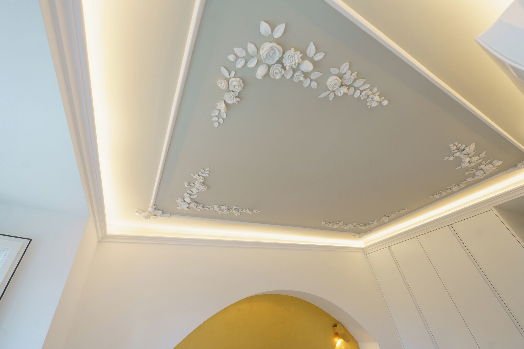 Een plafond met bloemdecoraties en inbouwspots.