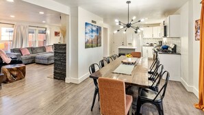 A spacious living area with a dining table, sofas, and a kitchen in the background. - Family Retreat - Backyard Games + Movie Room - Sleeps 16 (Orem)