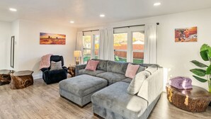 A living room with a sectional sofa, a chair, a coffee table, and a plant. - Family Retreat - Backyard Games + Movie Room - Sleeps 16 (Orem)