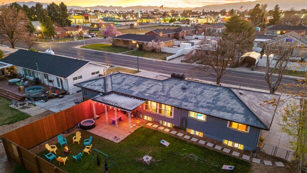 A residential area with houses, a swimming pool, and a patio with outdoor furniture. - Family Retreat - Backyard Games + Movie Room - Sleeps 16 (Orem)