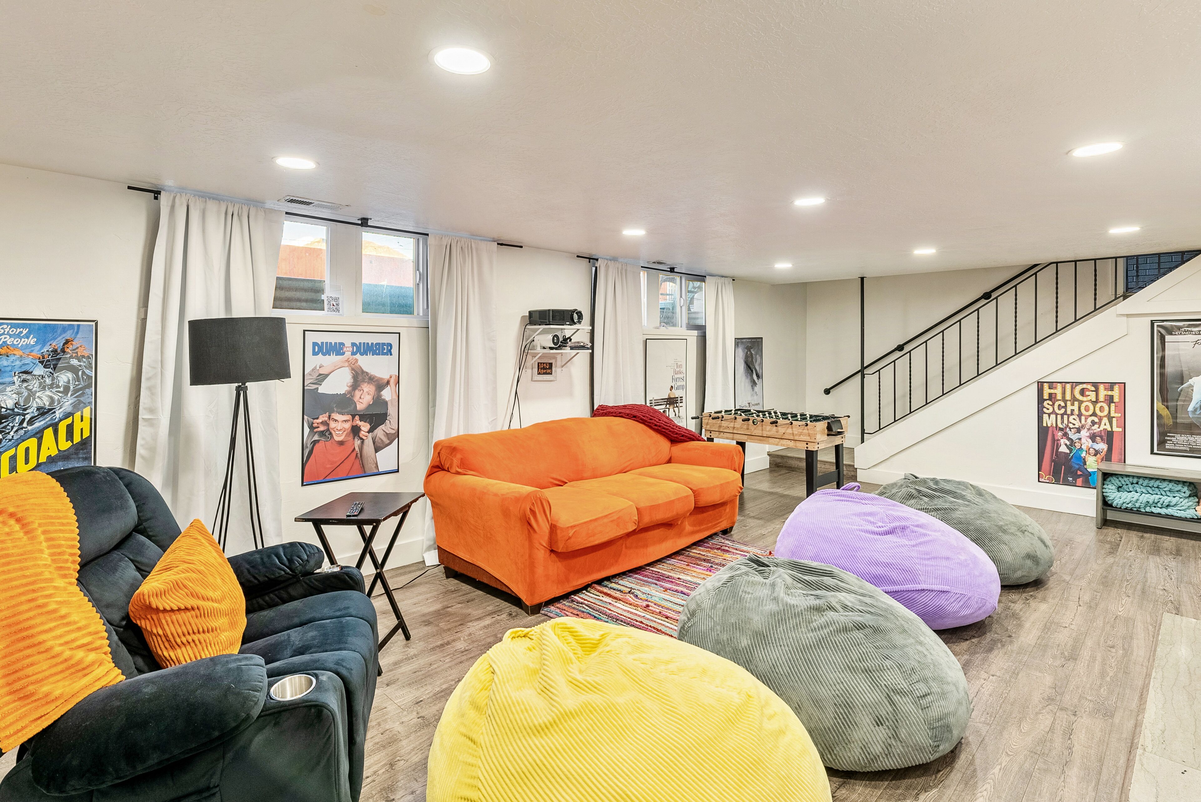 A living room with a sofa, bean bags, a lamp, and a staircase.