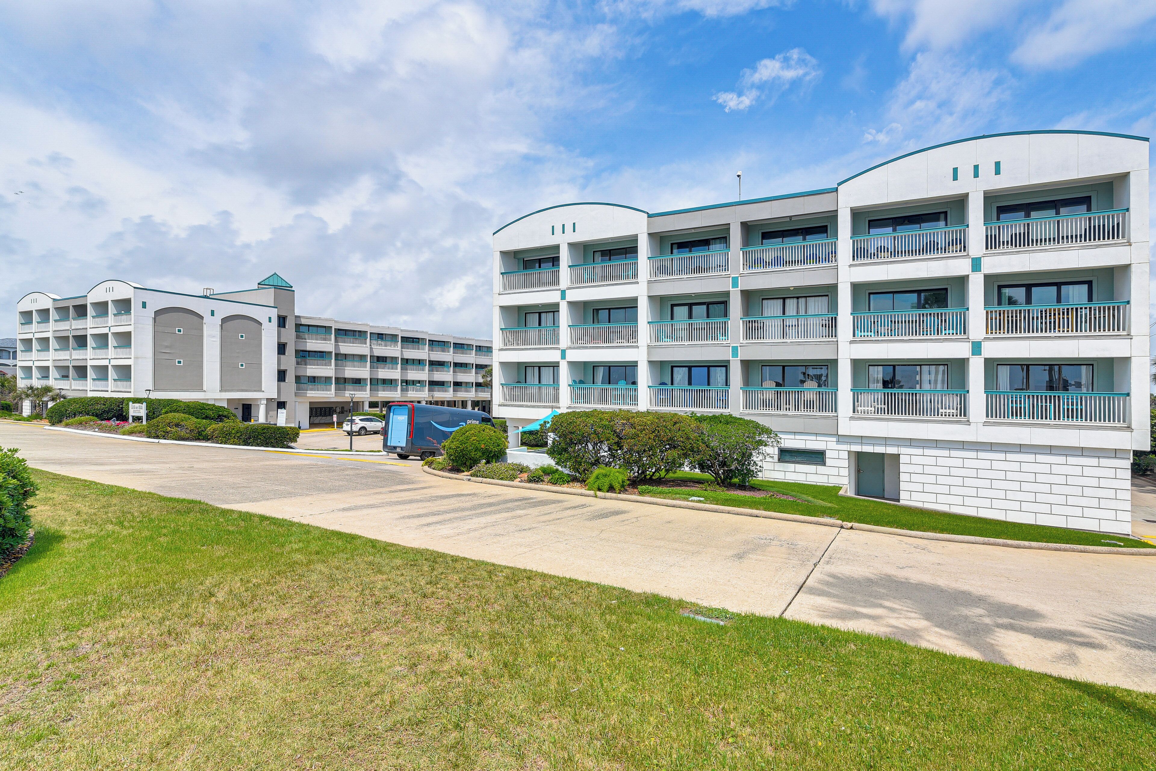 A modern hotel with multiple floors, balconies, and a parking area.