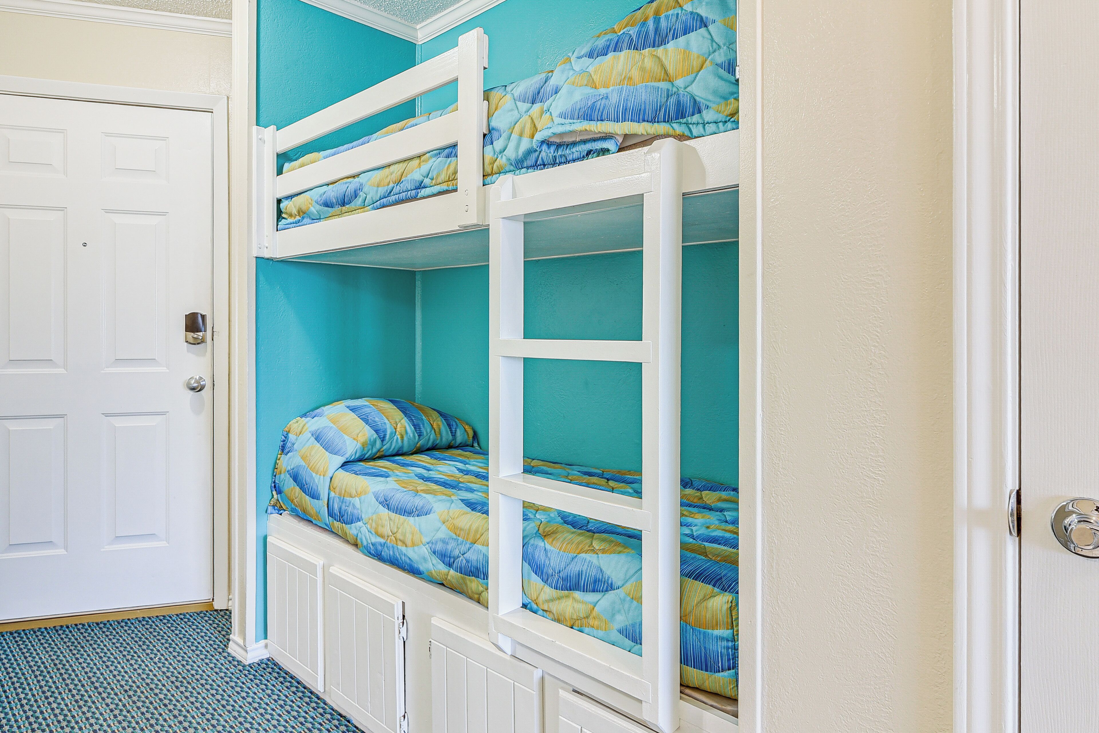 A bunk bed room with a teal wall and white trim.