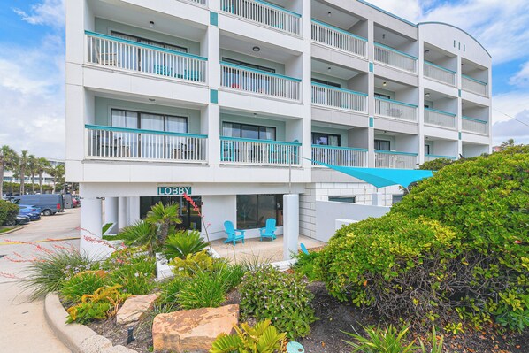 A multi-story hotel with balconies, outdoor seating, and a landscaped garden area. - Steps to Babes Beach: Condo w/ Pool in Galveston (Galveston)