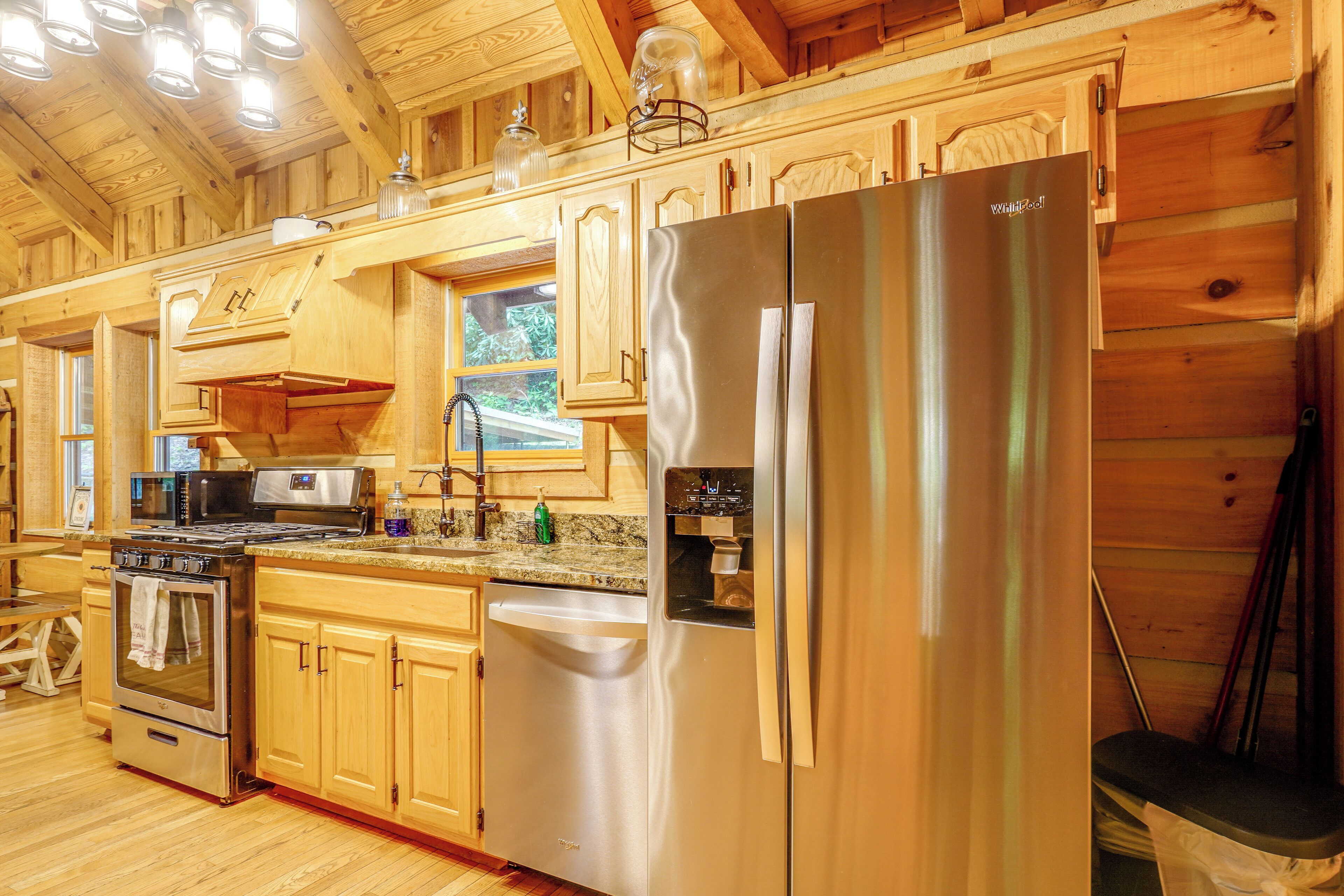 A modern kitchen with wooden cabinetry, stainless steel appliances, and a granite countertop.