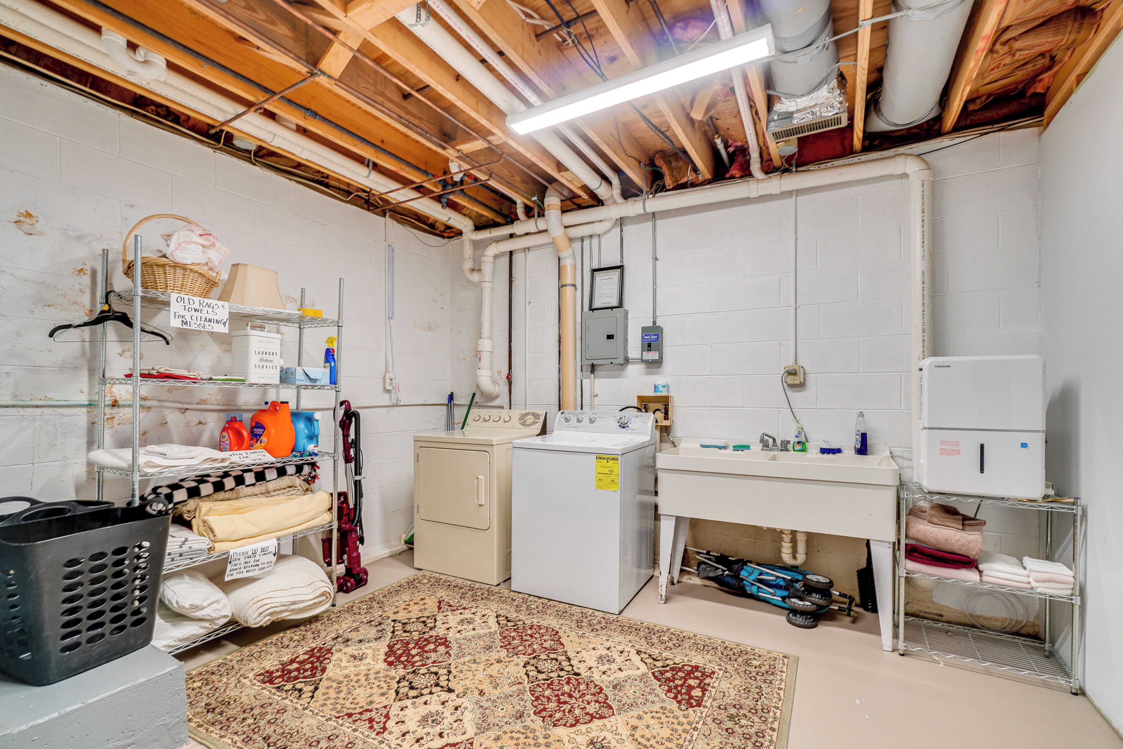 A laundry room with a washing machine, dryer, and shelves with towels and cleaning supplies.