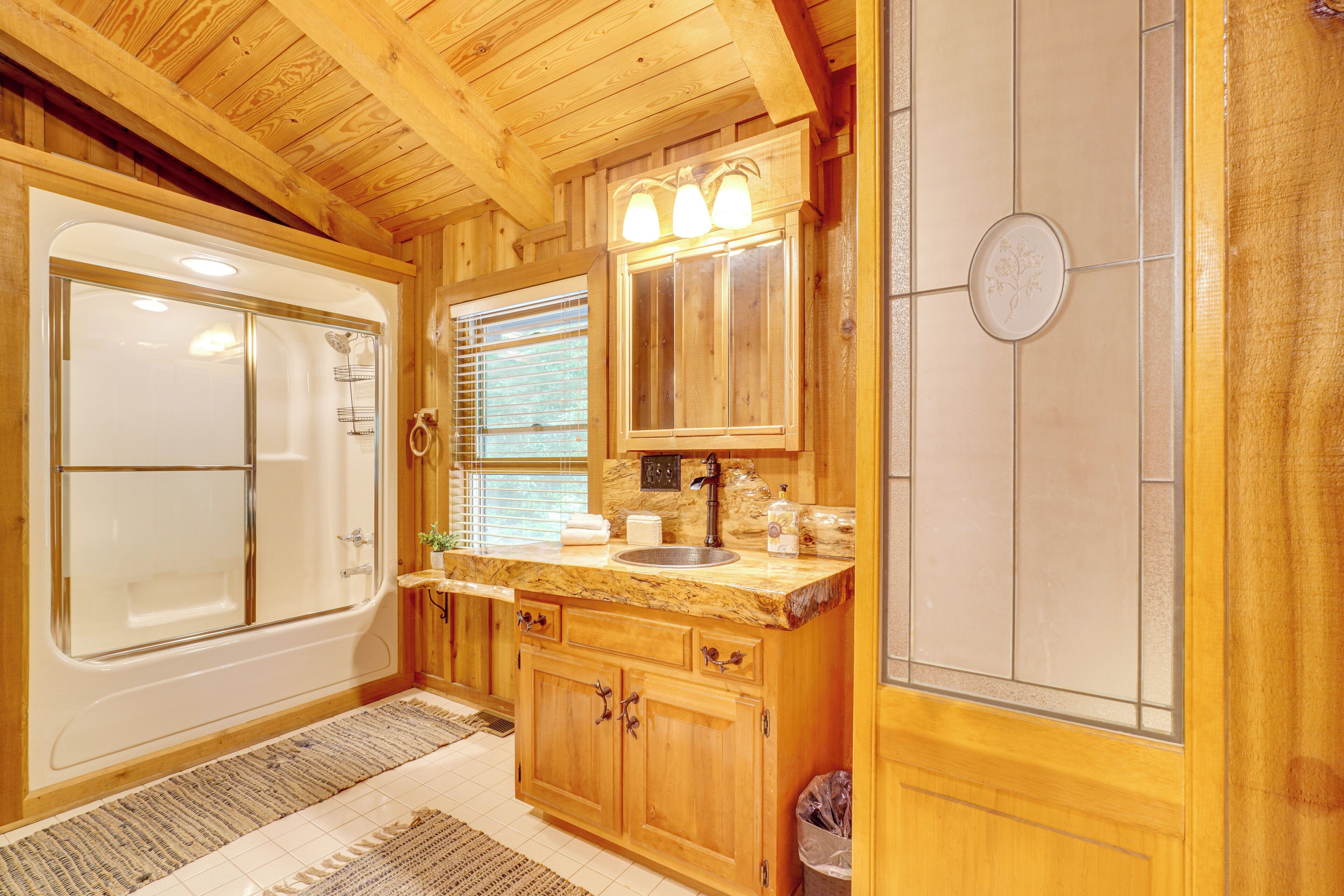 Un bagno in stile chalet in legno con vasca, mobile lavabo e lavandino.