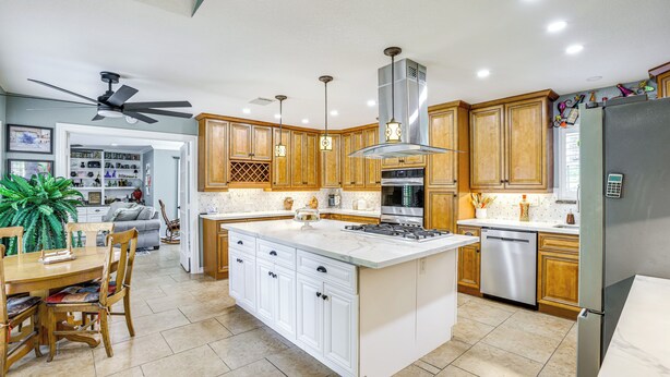 A modern kitchen with wooden cabinets, a large island, and stainless steel appliances. - Outdoor Kitchen & Hot Tub: Tranquil Home in Humble (Humble)