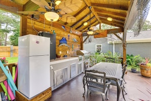 A covered outdoor kitchen with a refrigerator, grill, and dining table. - Outdoor Kitchen & Hot Tub: Tranquil Home in Humble (Humble)