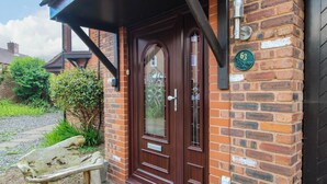A brick building with a dark wooden door, a mailbox, and a bench outside. - 63 Severn Street (Bridgnorth)