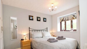 A bedroom with a bed, bedside tables, a mirror, wall-mounted pictures, a chandelier, and a window with a view. - 63 Severn Street (Bridgnorth)