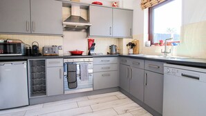 A modern kitchen with grey cabinets, a built-in oven, and a dishwasher. - 63 Severn Street (Bridgnorth)
