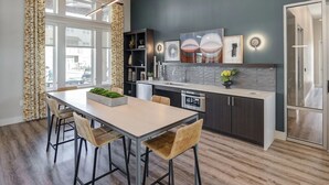 A modern kitchen with a dining area, featuring a large window, dark wall, and contemporary design elements. - Landing | Modern 1BD, Gym, Pool (Fate)