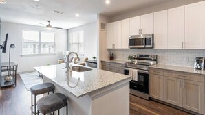 A modern kitchen with granite countertops, stainless steel appliances, and wooden cabinets. - Landing | Modern 1BD, Gym, Pool (Fate)