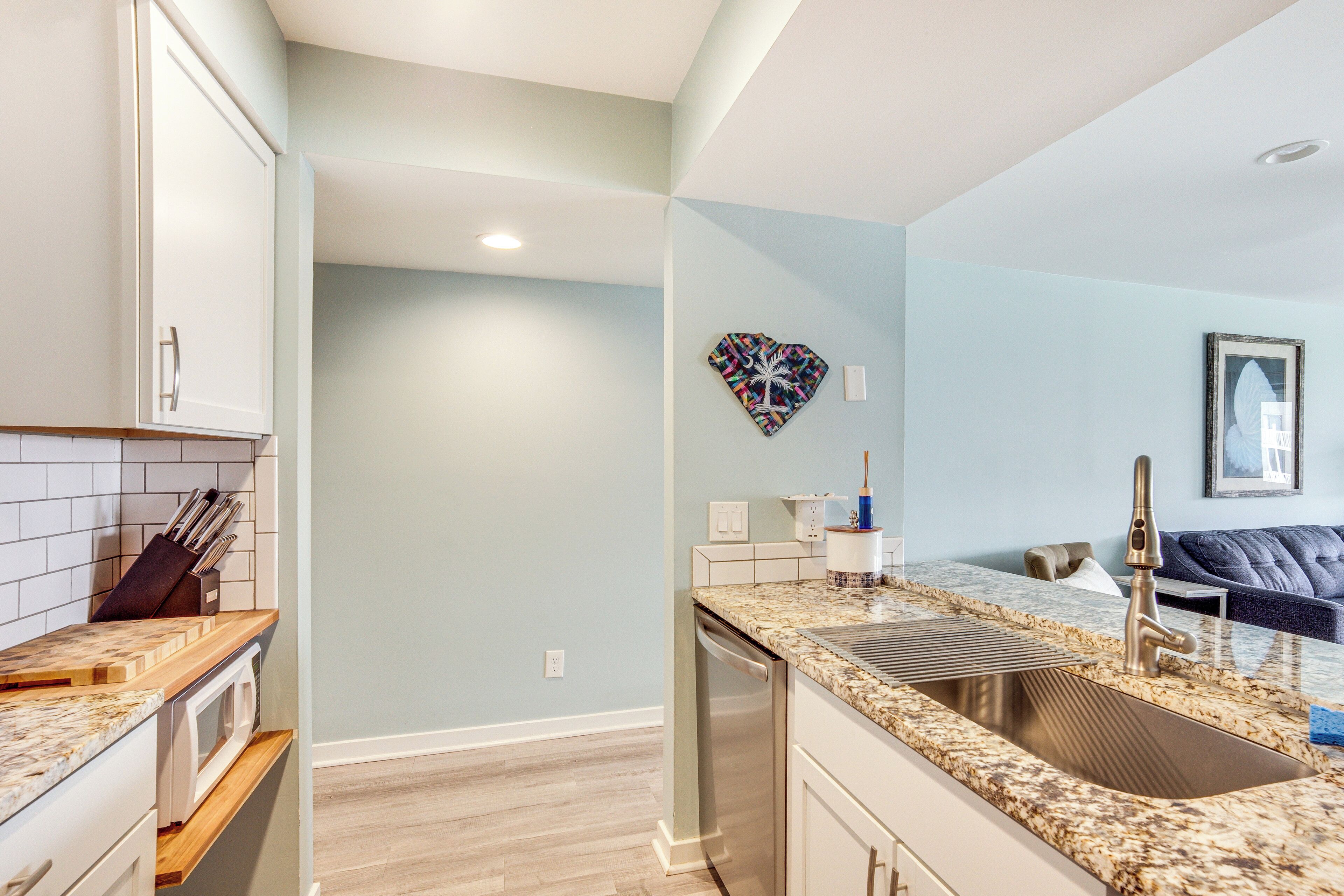 A modern kitchen with a granite countertop, stainless steel sink, and white cabinetry.