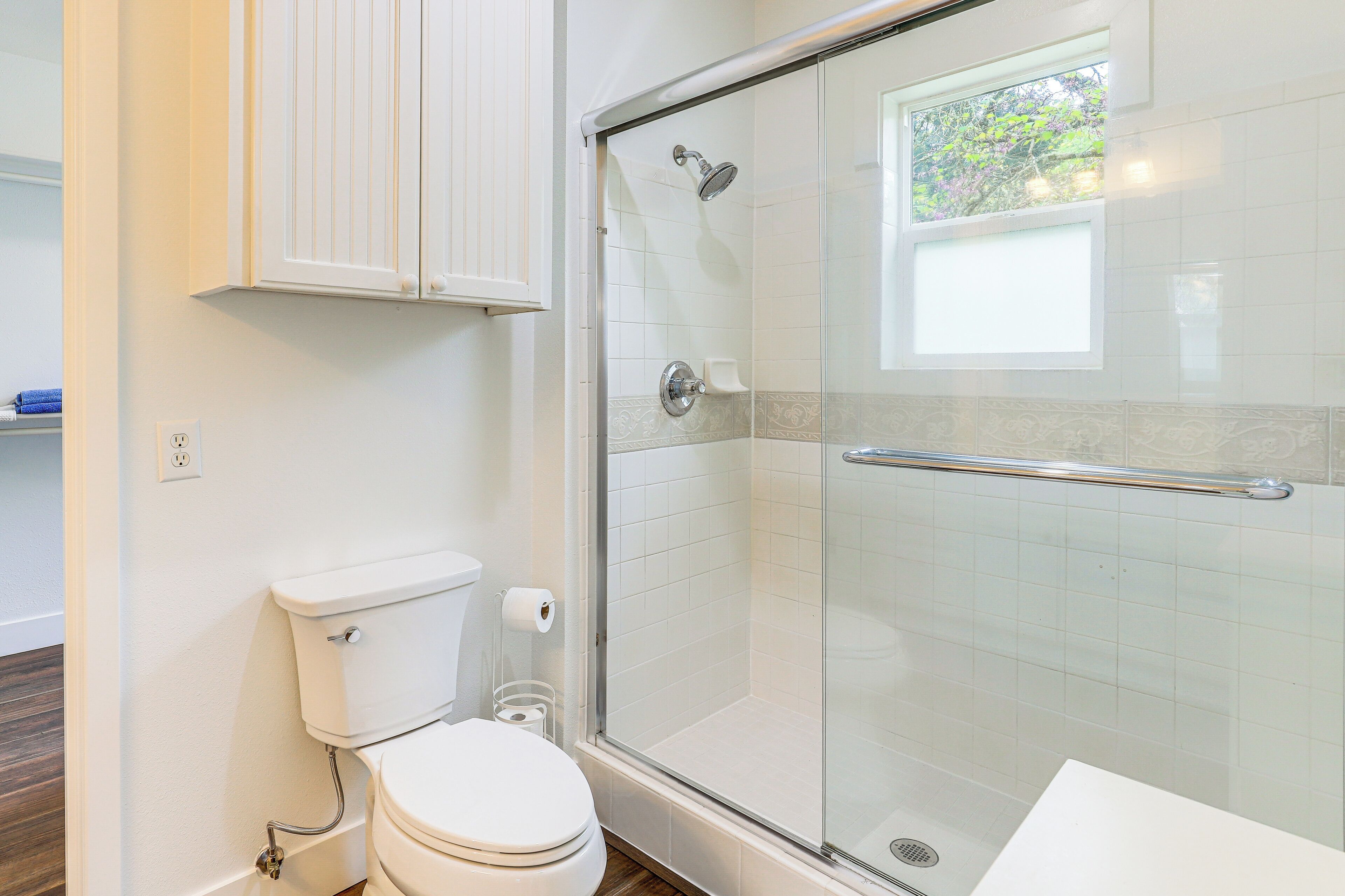 Ein Badezimmer mit Duschkabine, Toilette und Fenster.