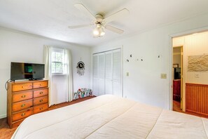 Enjoy a restful stay in this cozy room featuring a large bed, dresser, flat-screen TV, and ceiling fan.