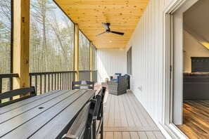 A wooden deck with a ceiling fan, a bench, and a wicker sofa.