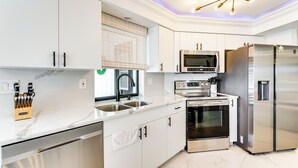 Une cuisine moderne avec des meubles blancs, des appareils en acier inoxydable, un four encastré et un four à micro-ondes.