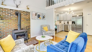 Un salón espacioso con chimenea, muebles con diseños y una cocina al fondo.