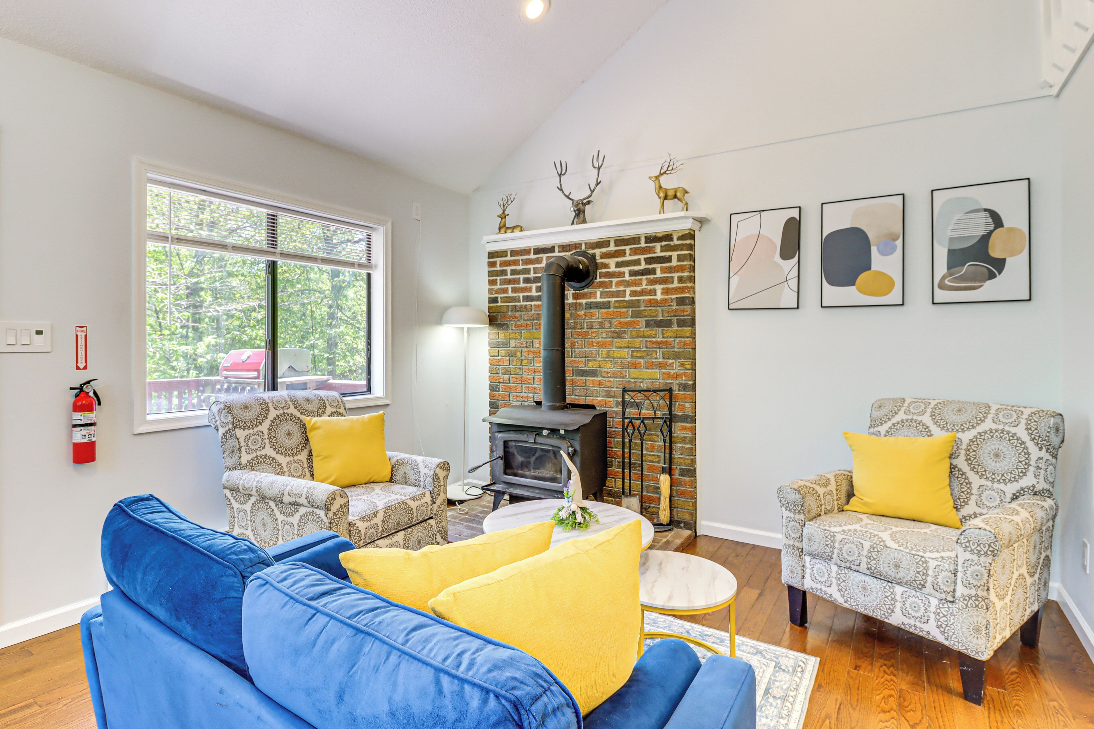Een woonkamer met een blauwe bank, gestreepten fauteuils, een open haard en kunst aan de muur.