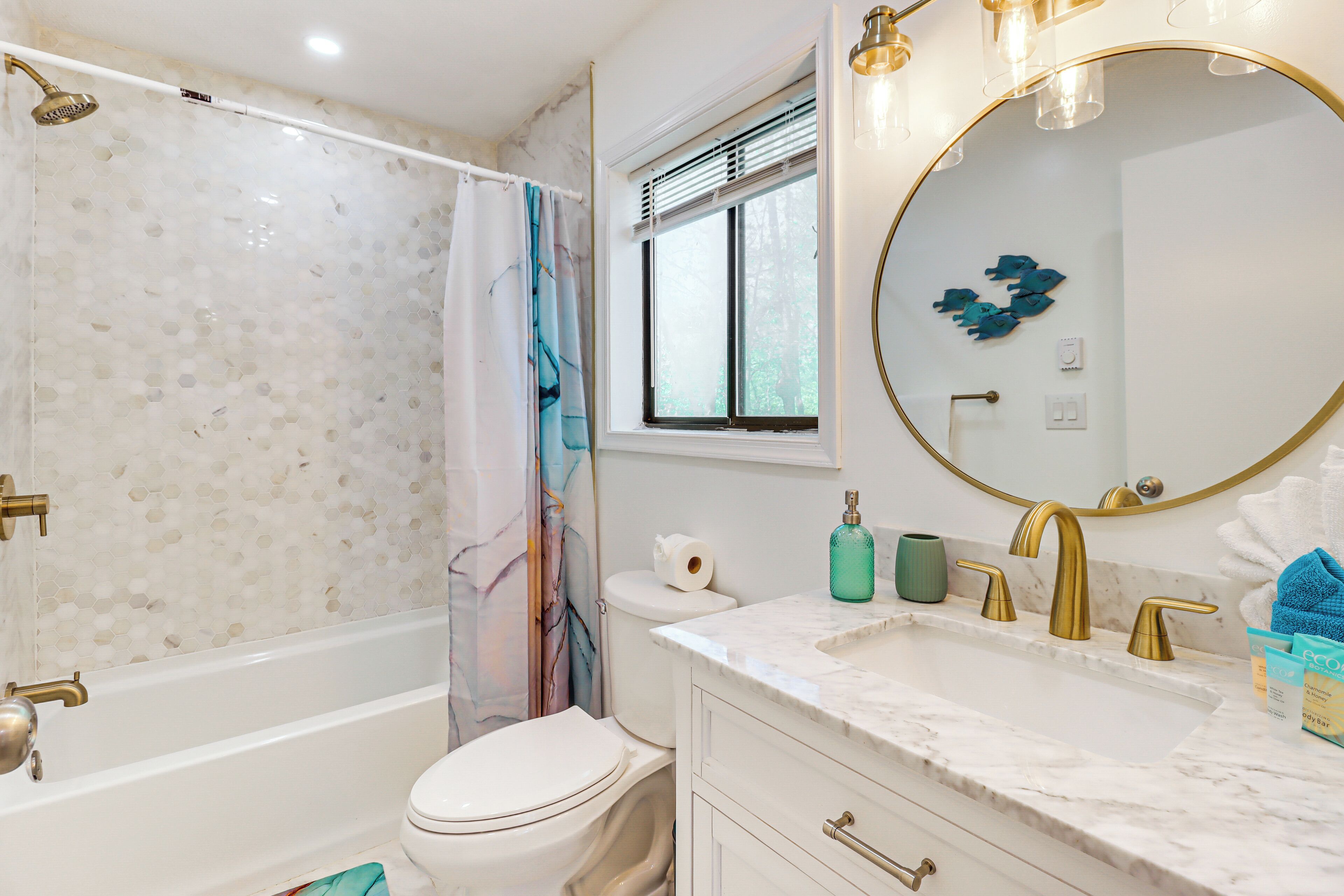 A bathroom with a bathtub, toilet, sink, and a large mirror.