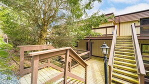 A wooden deck with a wooden staircase leading to a building. - Walk to Hiking & Skiing: Beech Mountain Condo (Banner Elk)