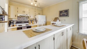 A kitchen with white cabinets, a white countertop, and a wine glass on a placemat. - Walk to Hiking & Skiing: Beech Mountain Condo (Banner Elk)