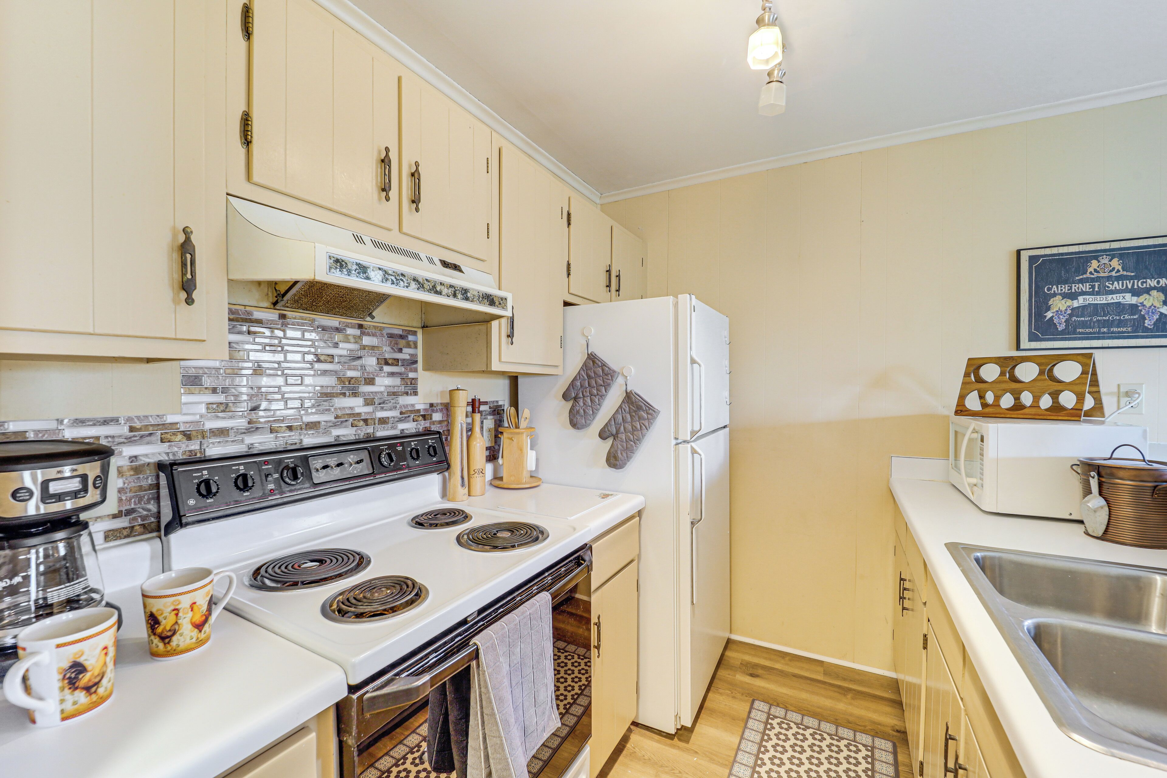 A kitchen with white cabinets, a stove, a refrigerator, and a microwave.