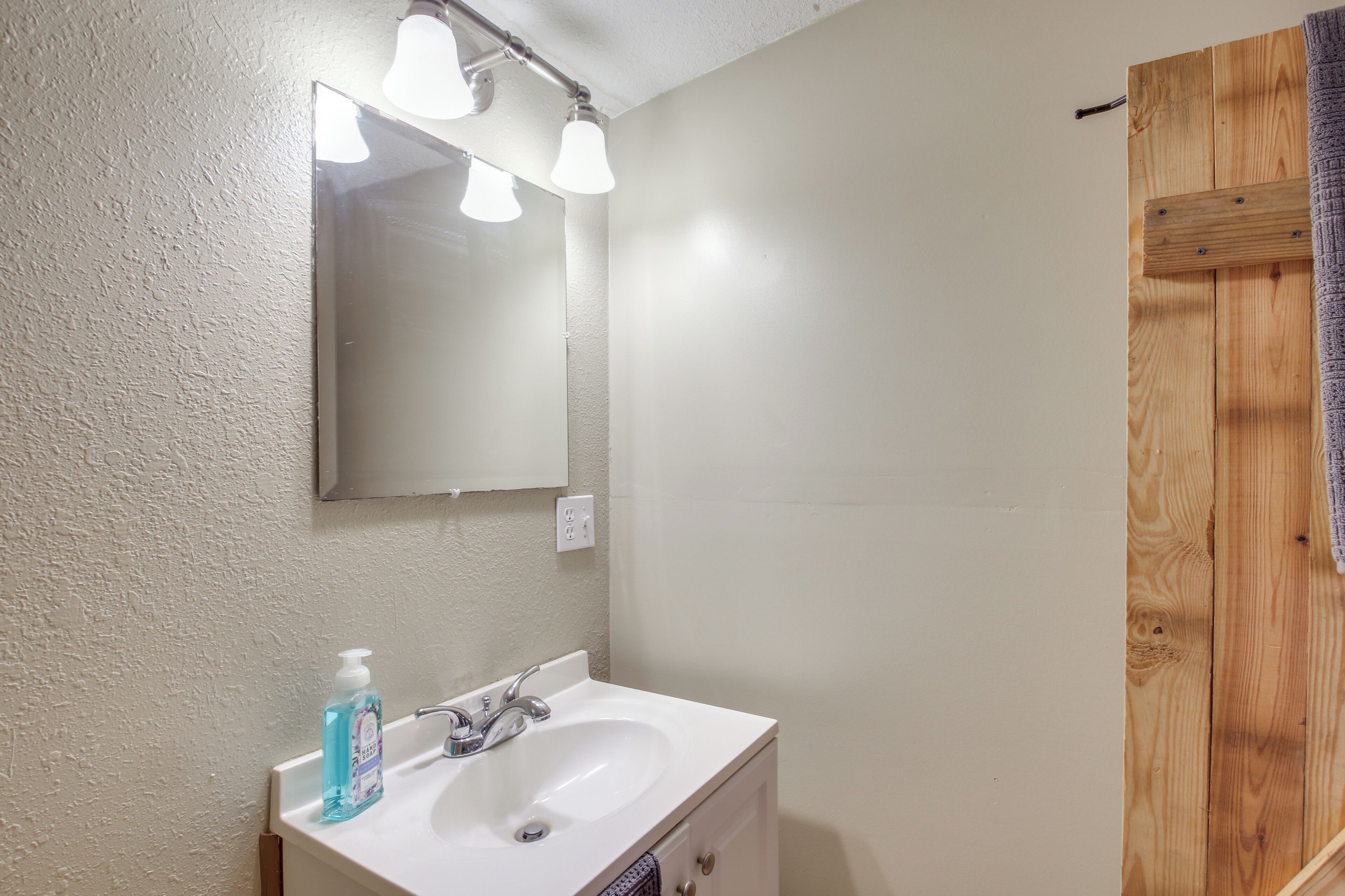 A bathroom with a white sink, a mirror, and a wooden door.