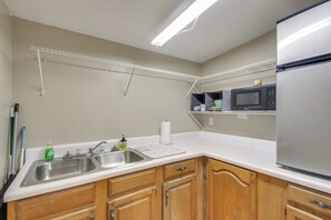 A kitchen with wooden cabinets, a stainless steel sink, a microwave, and a refrigerator. - Fishing Ponds, Trails & River Access: Jay Studio! (Jay)