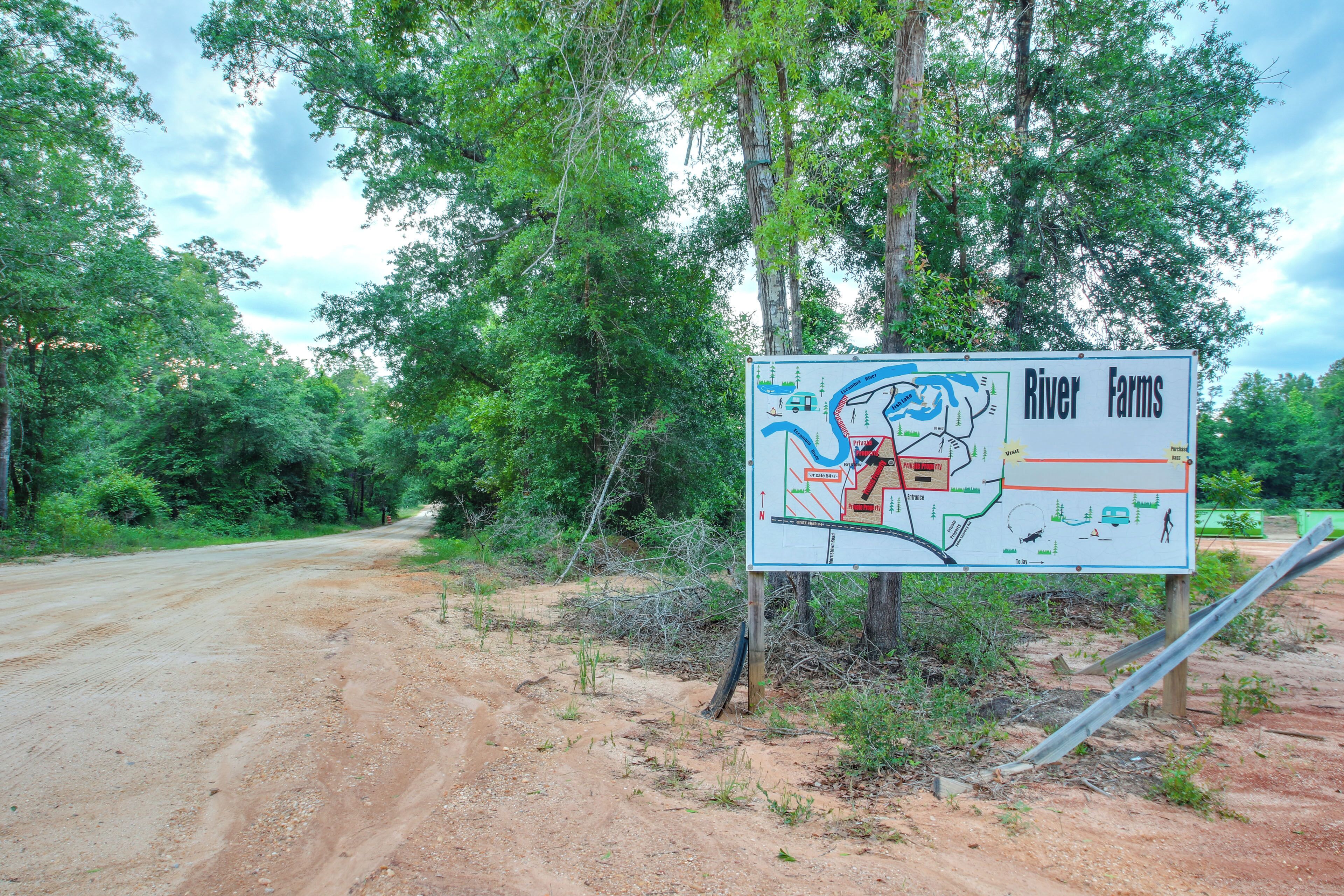 A dirt road leading to a signboard with a map and text indicating 'River Farms'.