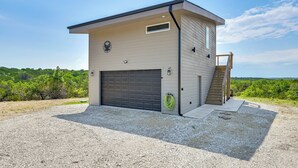 A modern single-story building with a garage, a small window, and a staircase leading to an upper level. - Hot Tub & Valley Views: Hidden Gem in Texas (Valley Mills)