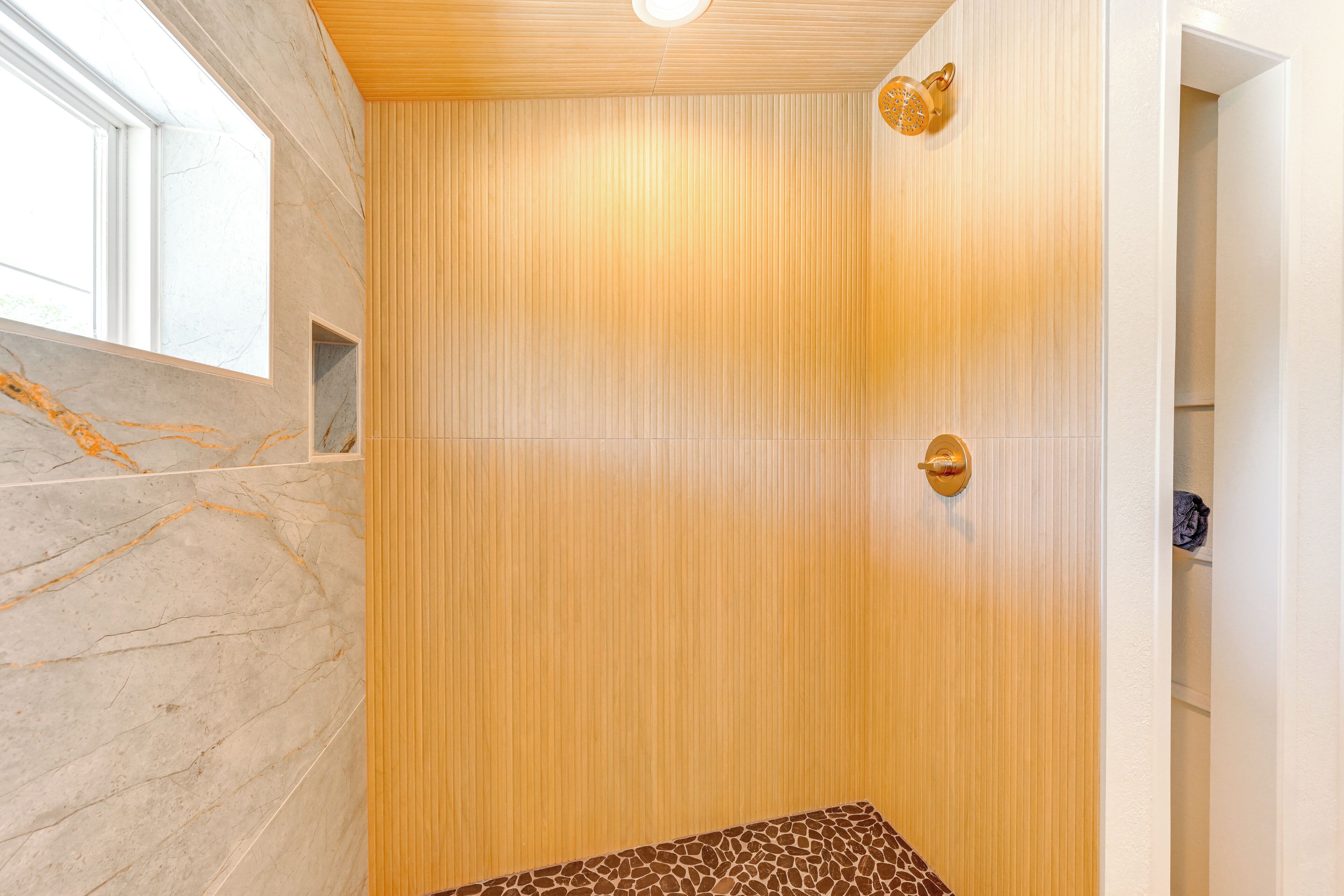 A modern bathroom with a wooden panel wall, a marble countertop, and a shower area.