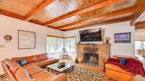 A living room with a leather sofa, a patterned rug, a fireplace, and a television. - Home 3 Mi to Main St Julian: Great for Groups! (Julian)