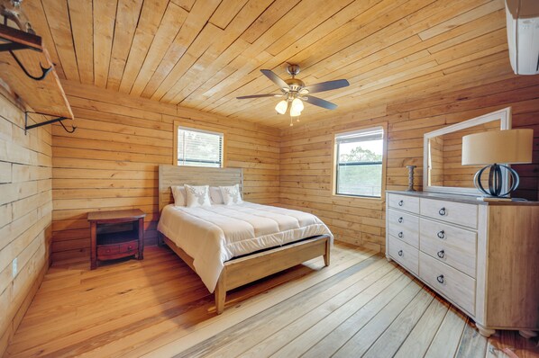 A wooden-paneled bedroom with a bed, dresser, and ceiling fan. - Pet-friendly Hideaway 13 Mi to Leakey (Leakey)