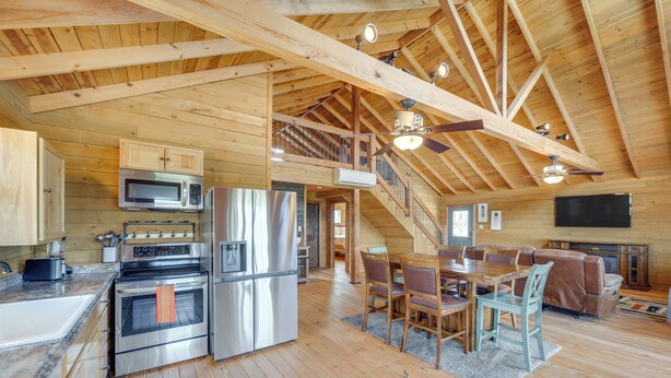 A spacious kitchen with stainless steel appliances, a dining area with wooden furniture, and a living room with a fireplace. - Pet-friendly Hideaway 13 Mi to Leakey (Leakey)